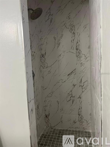 A shower with a marble wall and floor.