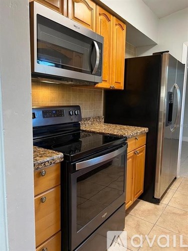 A kitchen with black appliances and wooden cabinets.