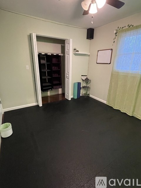 A room with a black floor and a white ceiling fan.