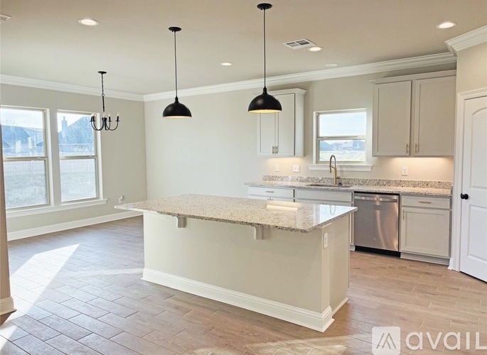 A kitchen with a granite countertop and pendant lights.