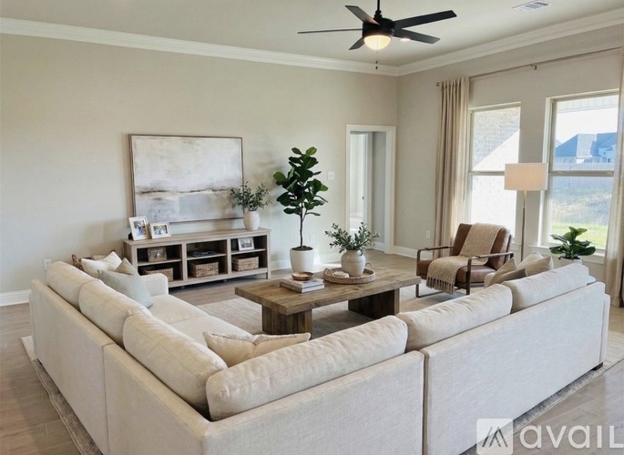 A living room with a large beige sofa, a wooden coffee table, and a ceiling fan.
