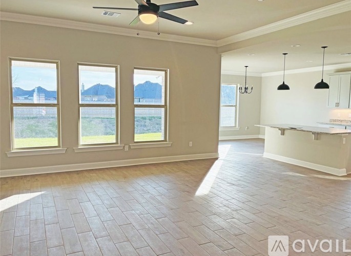 A spacious room with a ceiling fan and large windows overlooking a landscape.