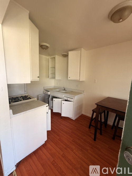 A kitchen with white cabinets and a wooden floor.