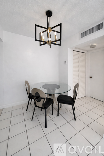 A modern dining room with a glass table and four chairs.