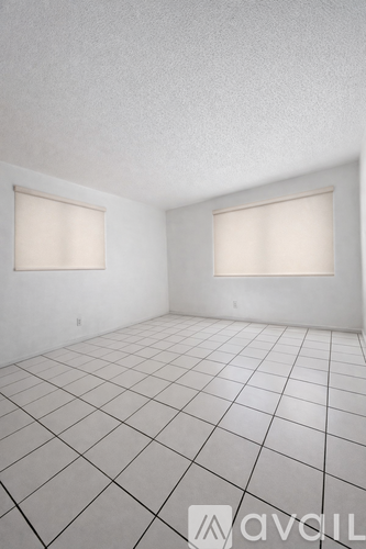 A room with white walls and a tiled floor with two windows.