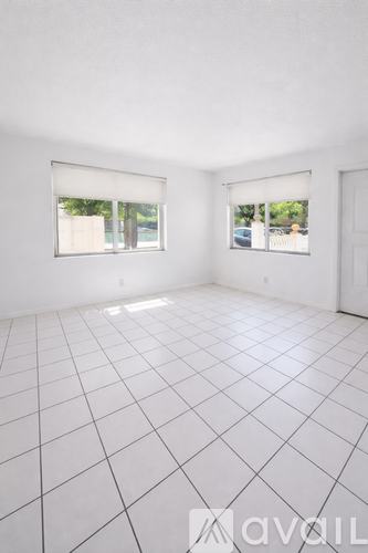 A white tiled room with two windows and a door.