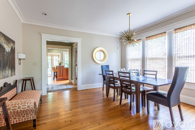 A dining room with a round gold mirror and a long table with chairs.