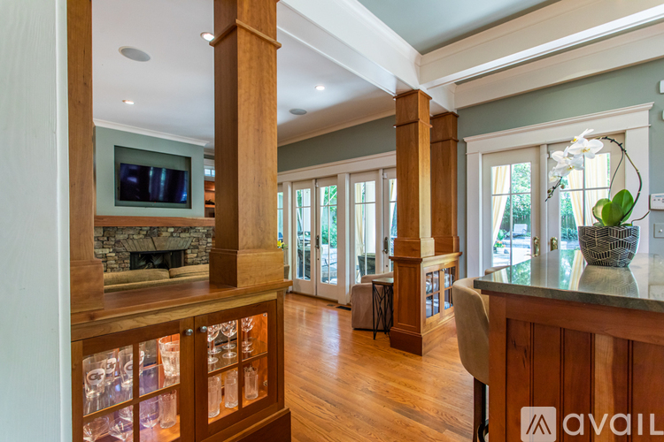 A spacious living room with a stone fireplace and a television mounted above it.