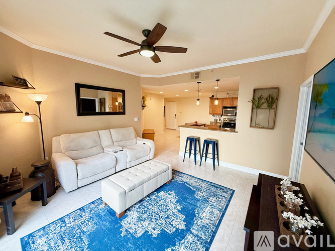 A living room with a white couch and a blue rug.