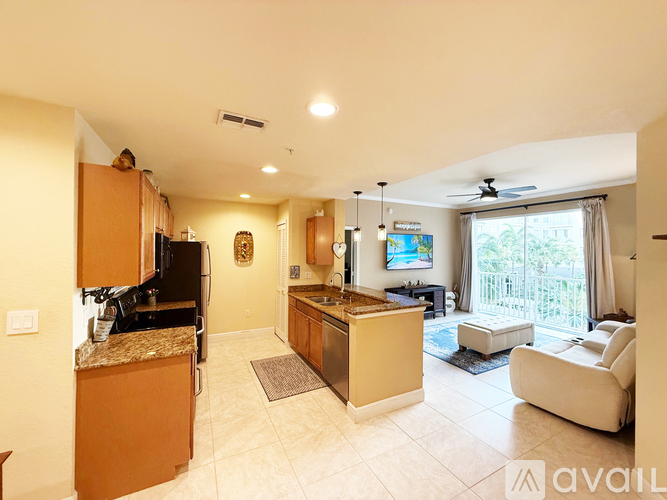 A kitchen with a refrigerator, sink, and a ceiling fan.
