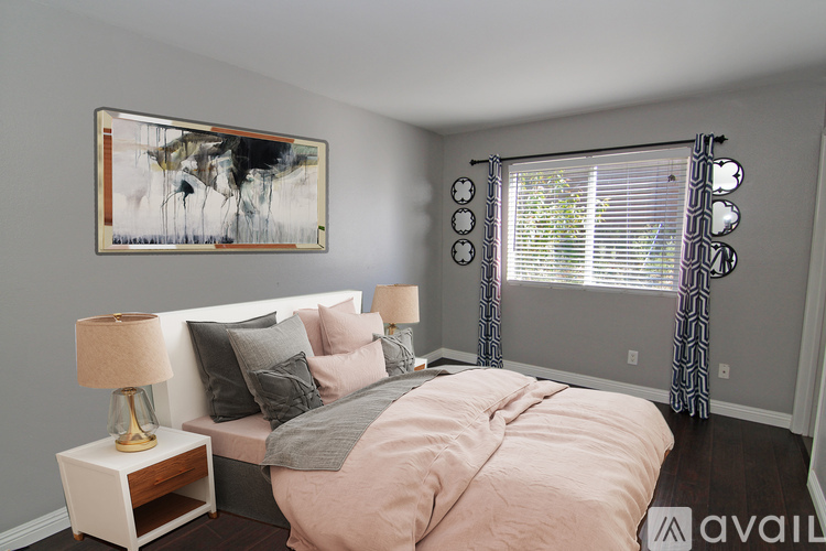 A bedroom with a bed, nightstand, and a painting on the wall.