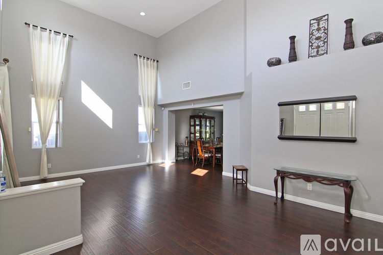 A spacious living room with hardwood floors and a large window with curtains.