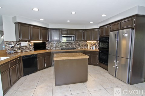 A kitchen with brown cabinets and a stone backsplash.