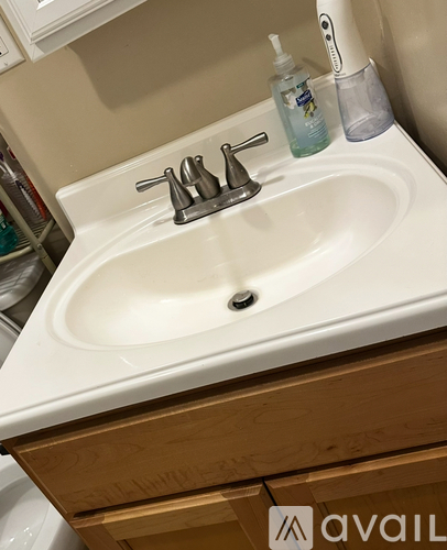 A white sink with a silver faucet and a bottle of mouthwash on the counter.