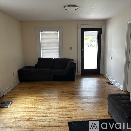 A living room with a black couch and wooden floors.