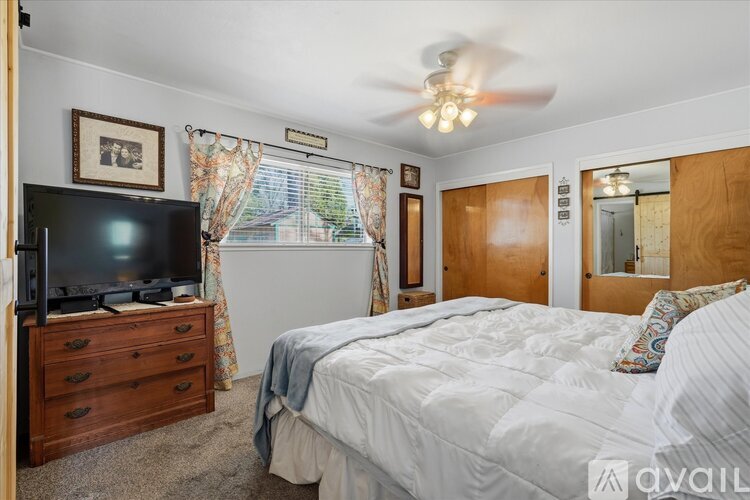 A bedroom with a bed, dresser, and television.