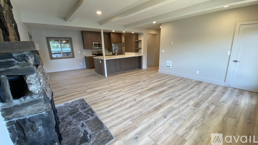 A modern kitchen with wooden floors and a stone fireplace.