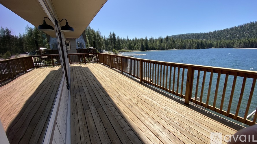 A wooden deck overlooking a lake with trees in the background.