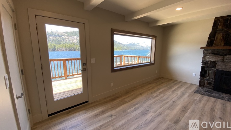 A room with a fireplace and a view of a lake through a window.