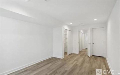 A long hallway with white walls and wood flooring.