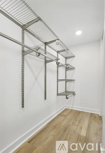 A white wall with a metal shelving unit on wheels.