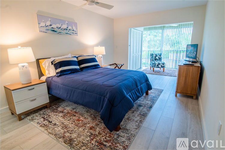 A bedroom with a blue bedspread and a painting on the wall.
