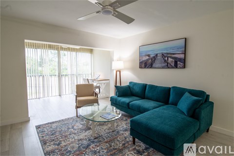 A living room with a blue couch, a chair, a coffee table, and a painting on the wall.