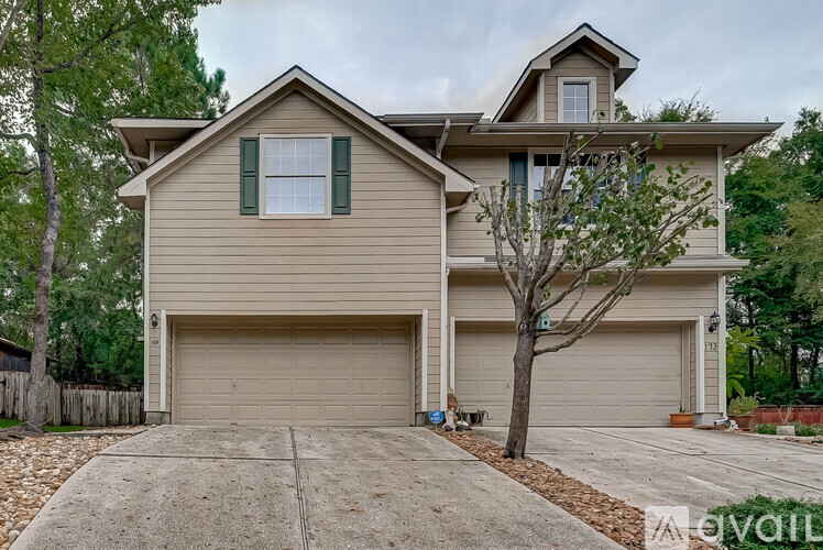 A two-story house with a garage and a tree in front.