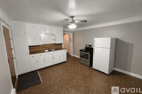A kitchen with white cabinets and a black refrigerator.