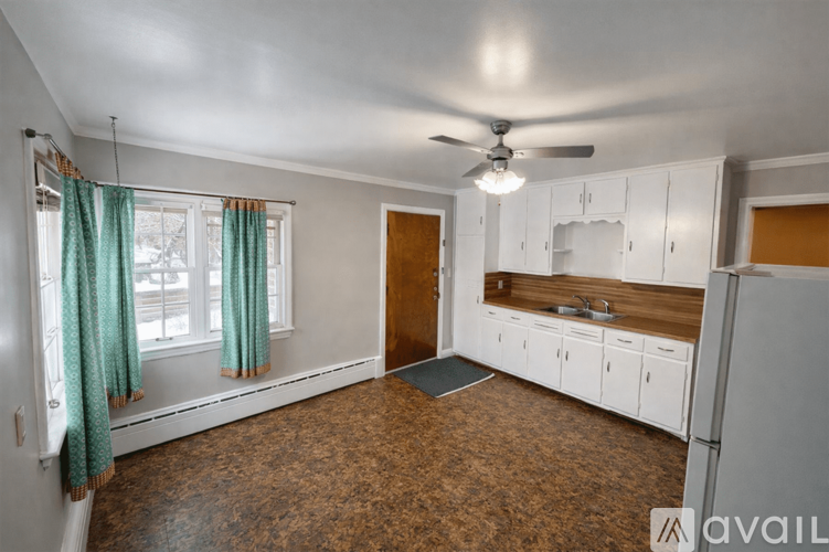A kitchen with white cabinets and a brown floor.