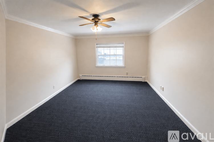 A room with a ceiling fan and carpeted floor.