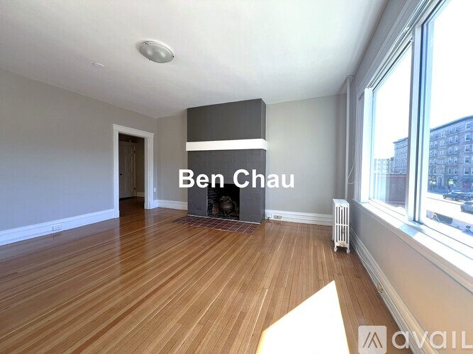A room with wooden floors and a large window with a view of a city skyline.