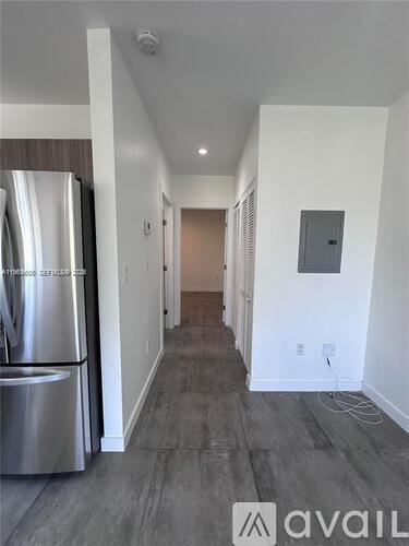 A long hallway with a stainless steel refrigerator on the left.