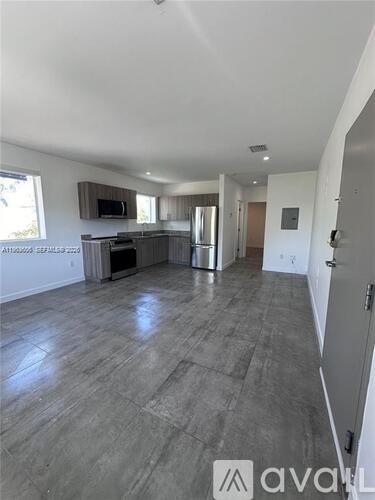 A spacious living room with a grey floor and white walls.