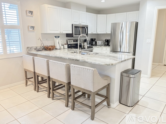 A kitchen with white cabinets and a marble countertop.