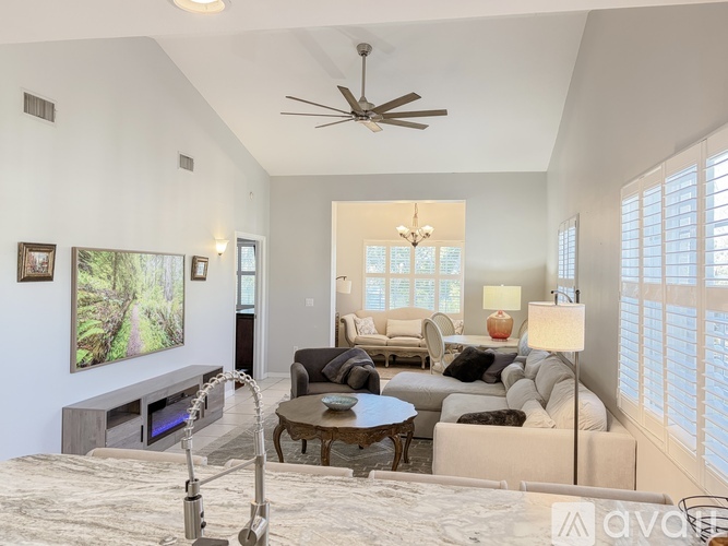 A living room with a ceiling fan and a large painting on the wall.