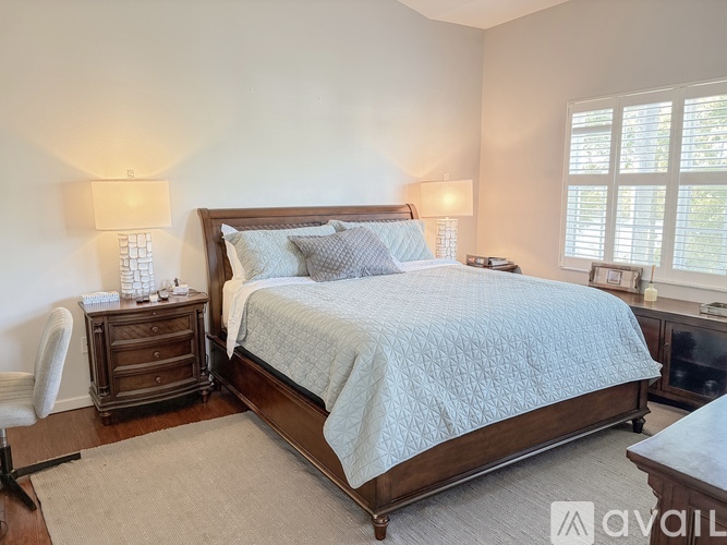 A bedroom with a large bed and a chair.