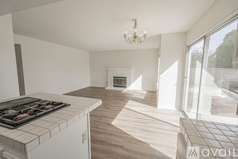 A modern kitchen with a stove top oven and a chandelier.