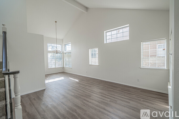 A spacious room with wooden floors and three windows.