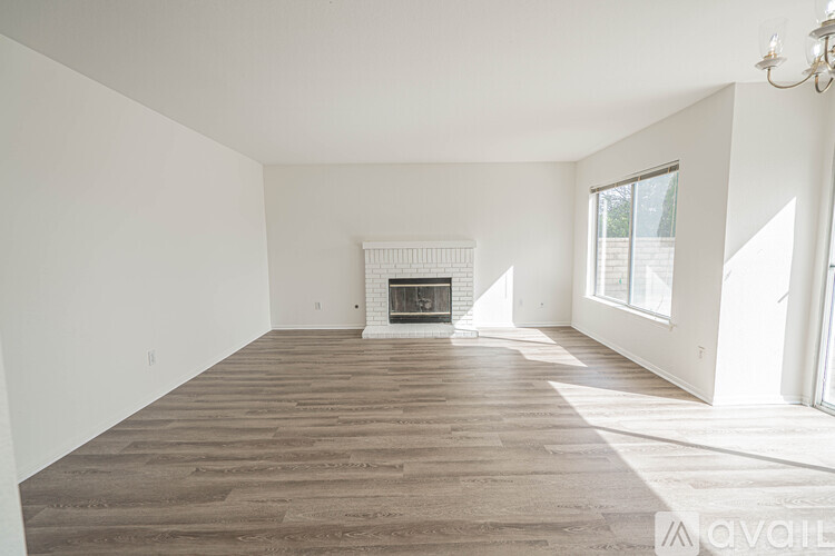 A spacious living room with a fireplace and wood flooring.