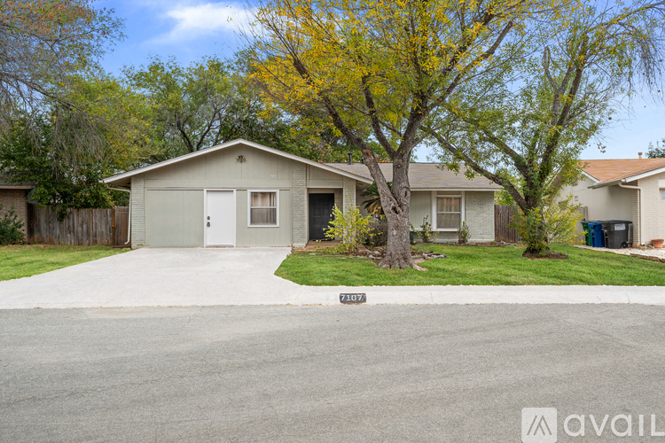 A house with a driveway and a tree with yellow leaves.