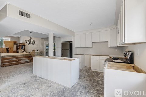A kitchen with white cabinets and a countertop is available for rent.