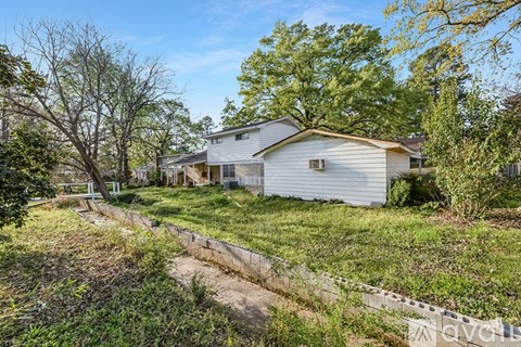 A house with a grey roof and a white fence in front of it.