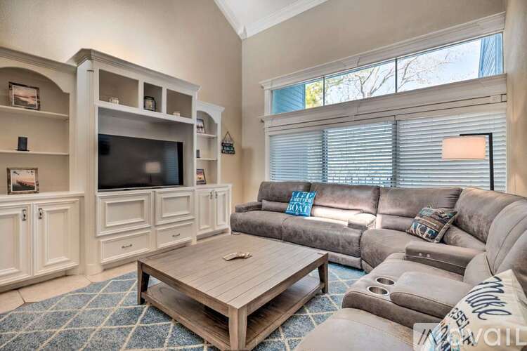 A living room with a grey couch, a wooden coffee table, and a television.