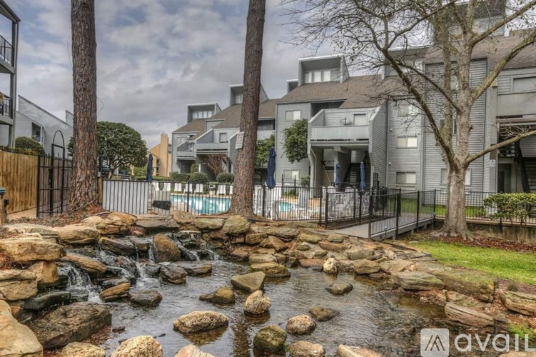 A stream flows through a rocky bed in front of a modern building.