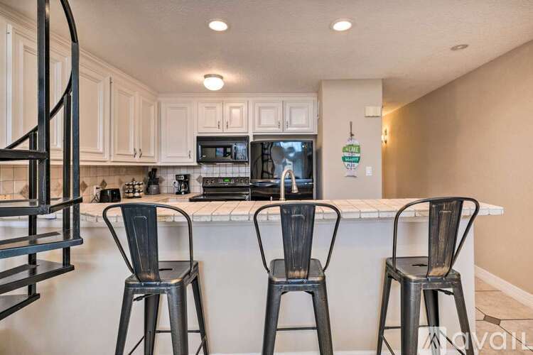 A kitchen with white cabinets and a black counter.