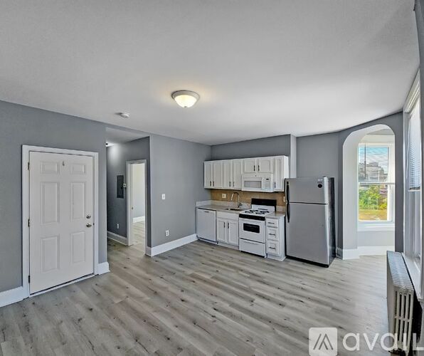 A kitchen with white cabinets and a wooden floor.