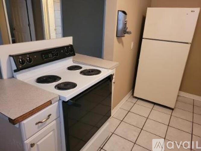 A white stove top oven with four burners and a white refrigerator in a kitchen.
