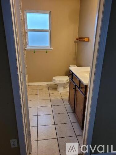A bathroom with a toilet, sink, and a window.