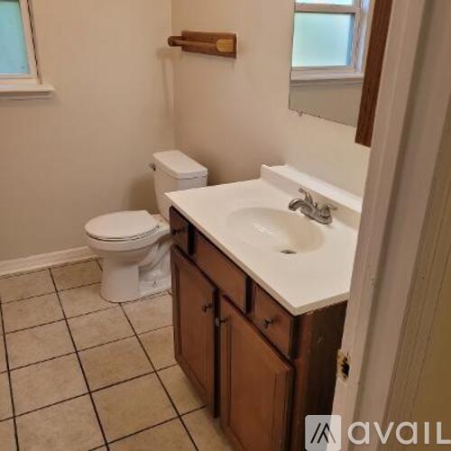 A bathroom with a toilet, sink, and wooden cabinets.